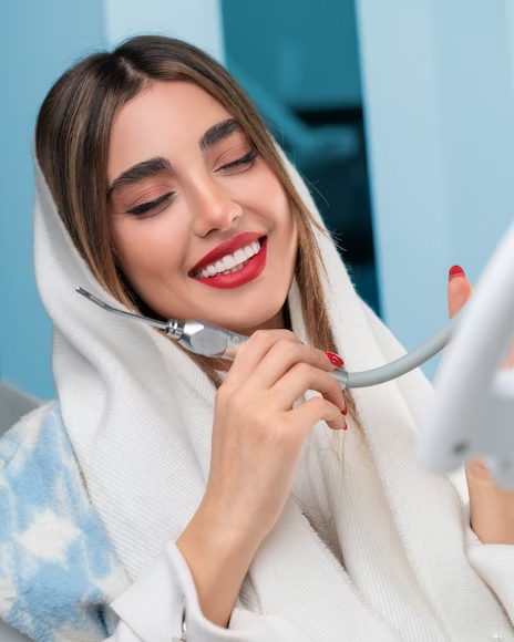 a beautiful woman smiling dreamily with white, healthy teeth while holding a dental tool