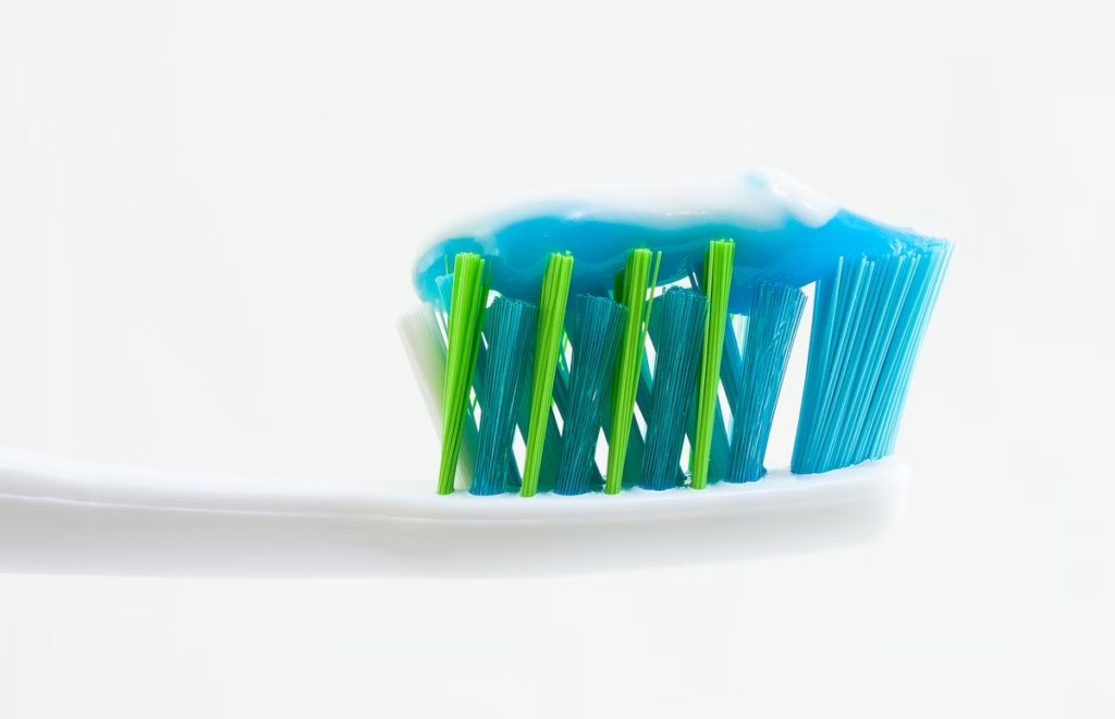 a green and blue bristled toothbrush with toothpaste on top