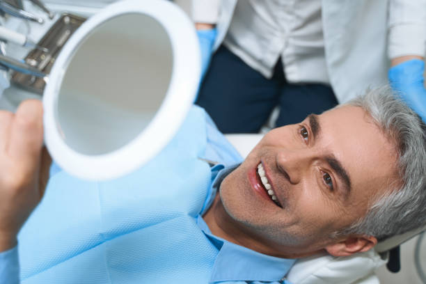 a man on a dental chair smiling at the mirror he's holding