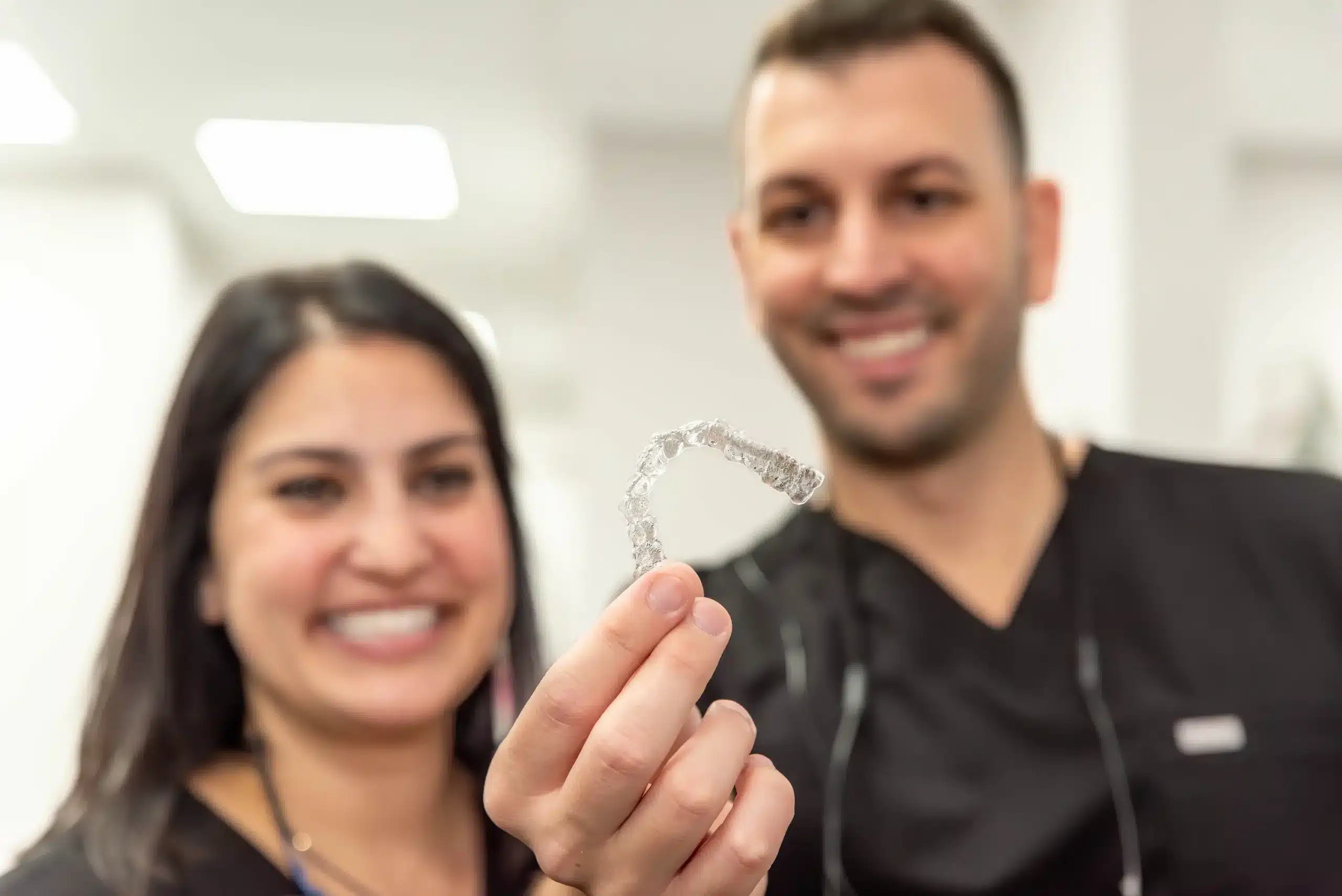 Dr. De Vincenzo and Dr. Saremi holding an invisalign clear aligner in addison, tx
